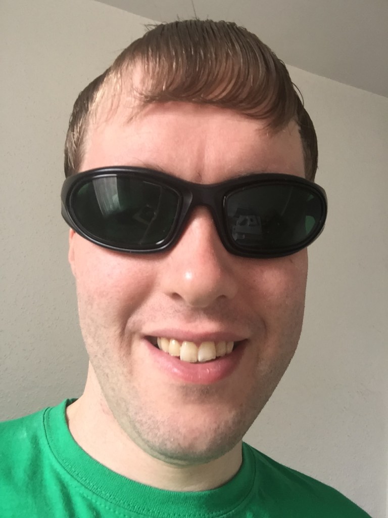 Selfie of me wearing green-tinted sunglasses and smiling.
