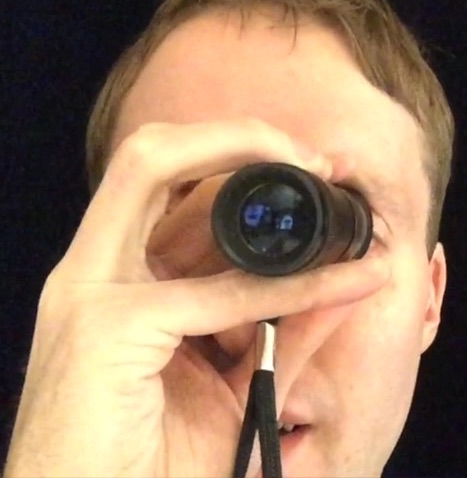 Image shows me holding my monocular - a small telescope - up to my eye