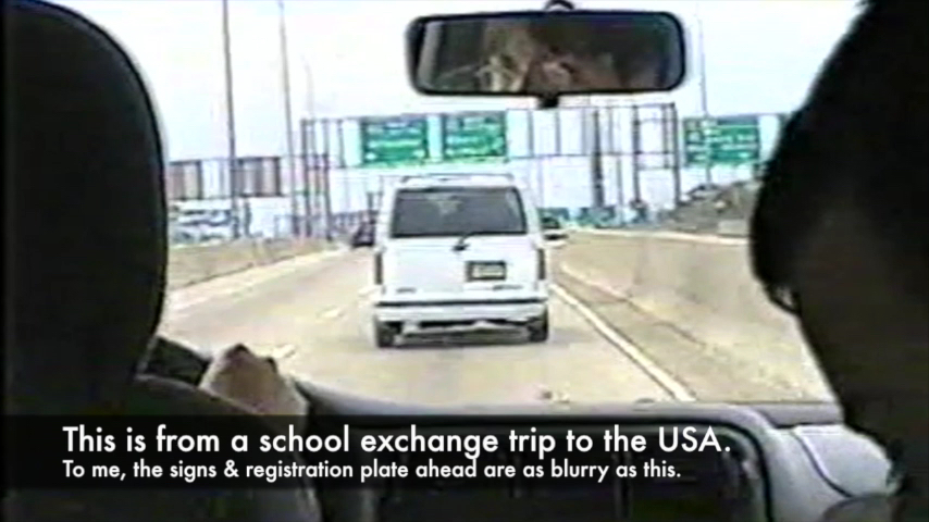 Image shows the view from inside a car on a motorway, where the signs and registration plates ahead of us are blurred. The caption says - This is from a school exchange trip to the USA. To me, the signs and registration plate ahead are as blurry as this.