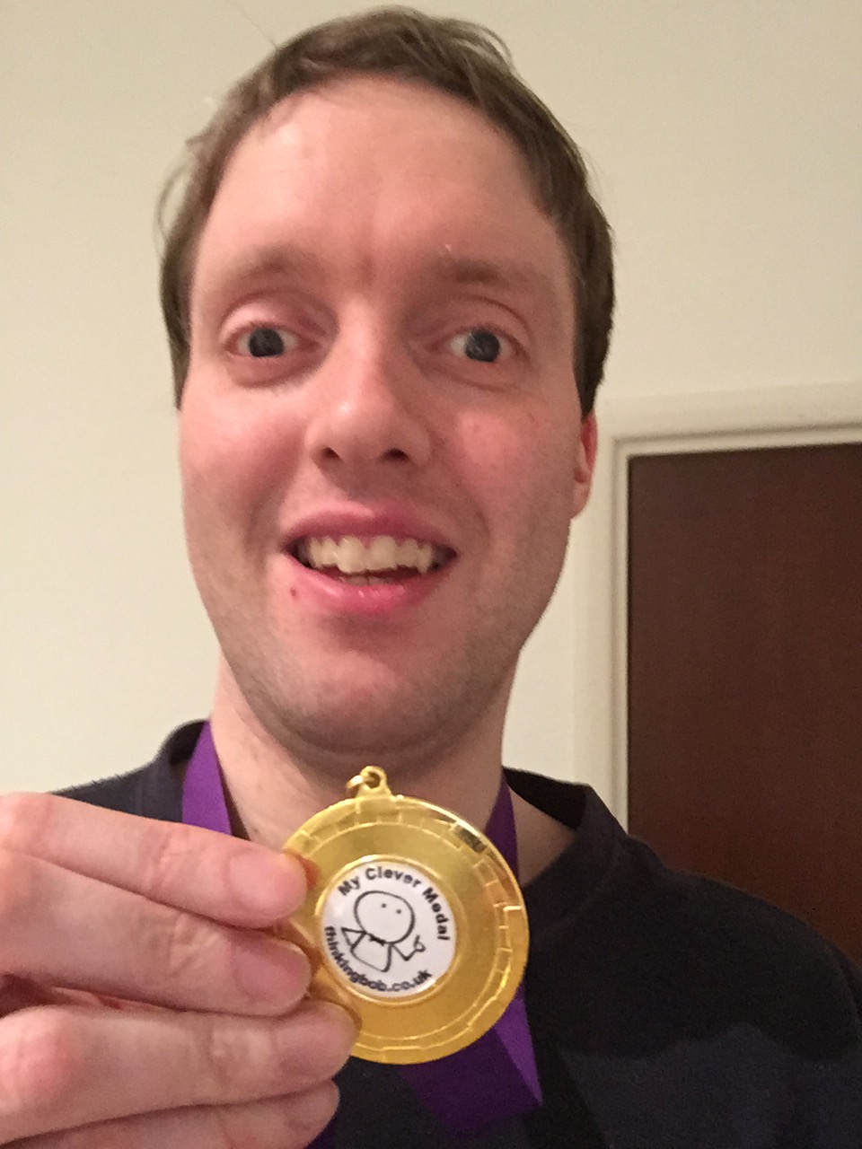 Glen wearing his Thinking Bob medal. Gold surrounds a white circle in the centre, which contains the text My Clever Medal - thinkingbob.co.uk