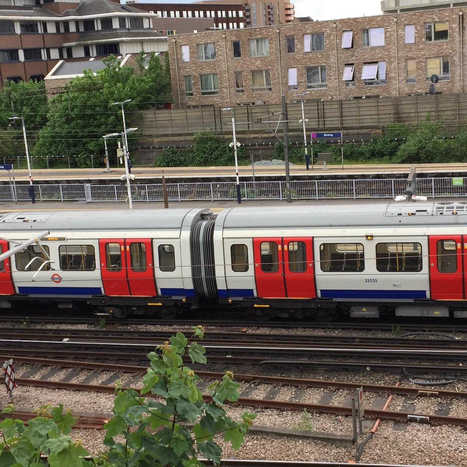 A District line train at Barking Station. The carriages are white with a blue stripe along the bottom and red doors.