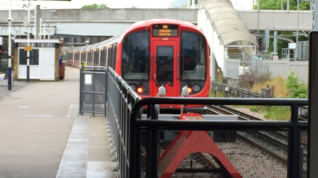 A District line train parked at the buffers at Barking Station, with red framing around its front windows.