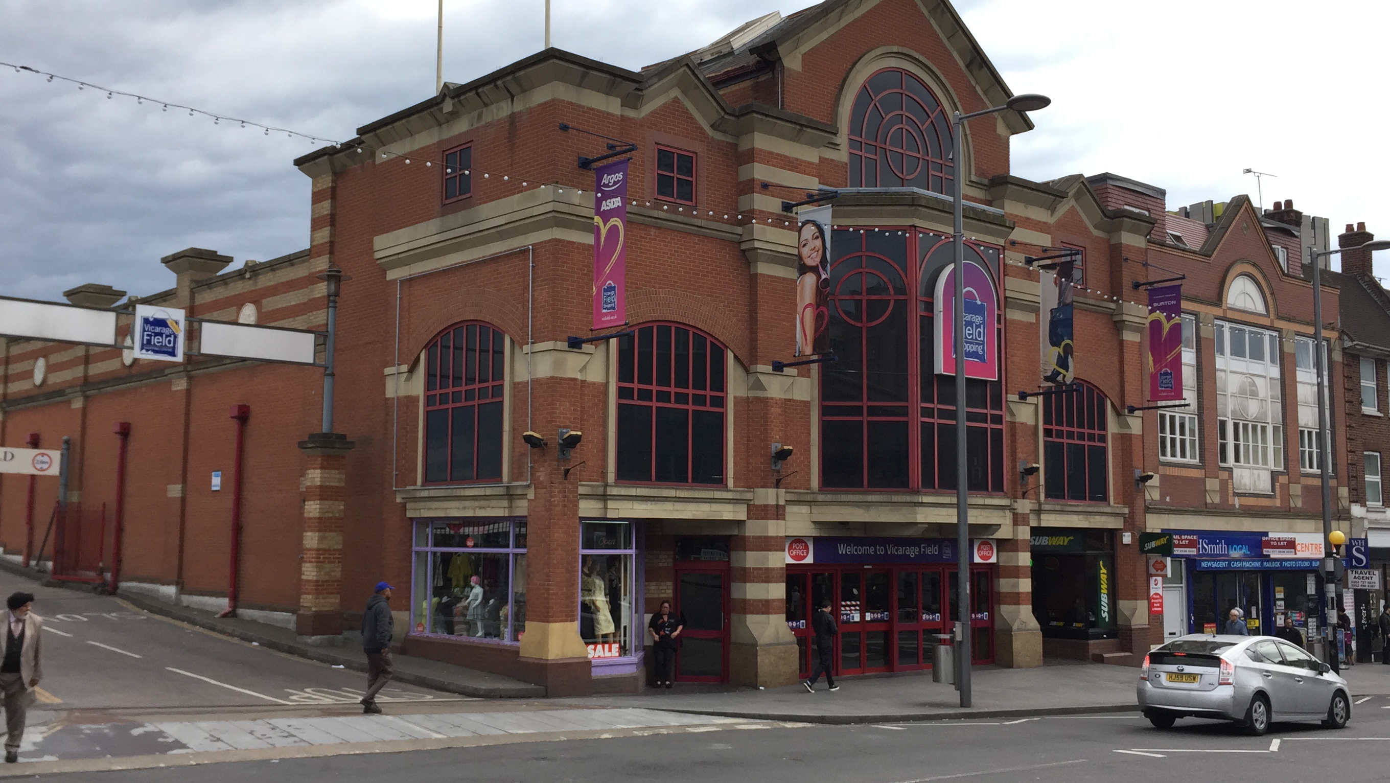 Vicarage Field Shopping Centre, a large red brick building with a very big window over the entrance, and much smaller ones on each side.