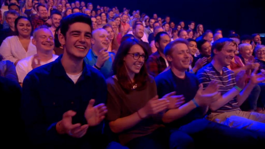Screenshot of the audience applauding on The Last Leg, including Glen on the right wearing a navy t-shirt with thin white and light-blue stripes.