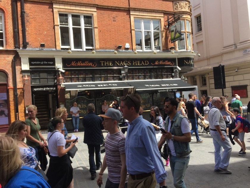 People walking past a pub called The Nag's Head.