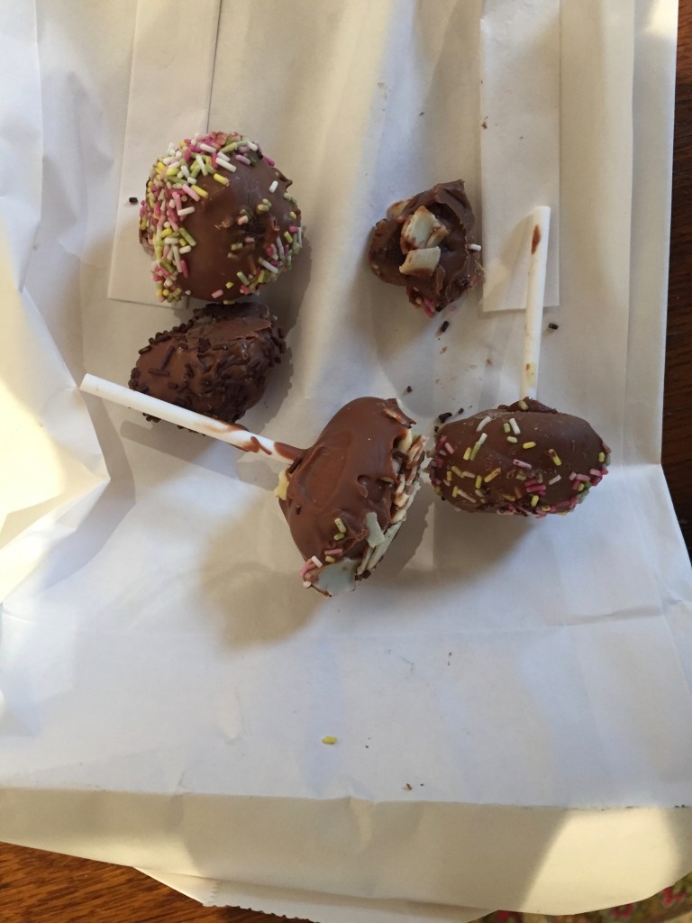 Chunky pieces of chocolate, a couple on lollipop sticks, sprinkled with hundreds and thousands