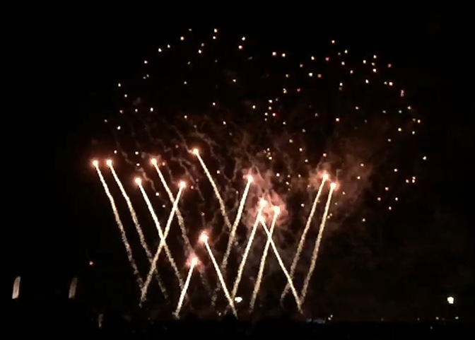 Many long-tailed bright fireworks, shooting upwards from the ground in overlapping diagonal lines.