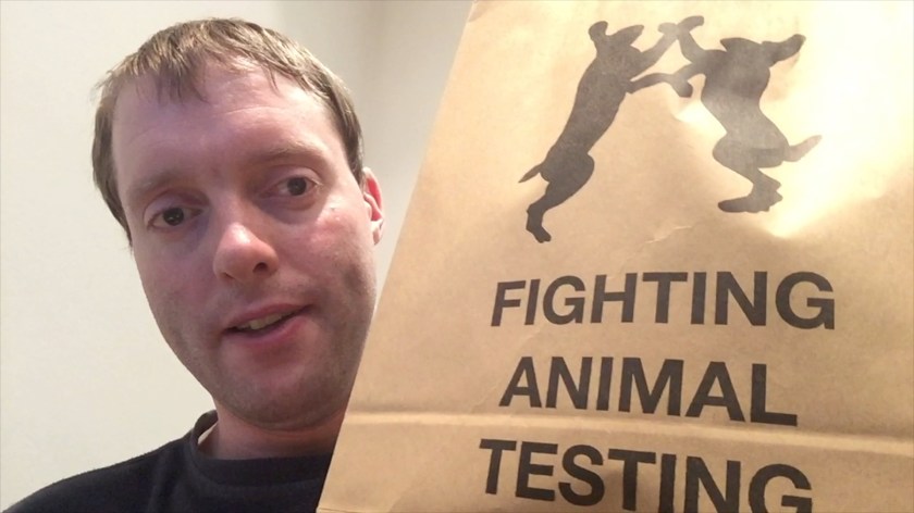 Me holding a large brown bag, which has a silhouette of 2 rabbits on their hind legs as they face each other, grasping each other's arms, above the words Fighting Animal Testing.