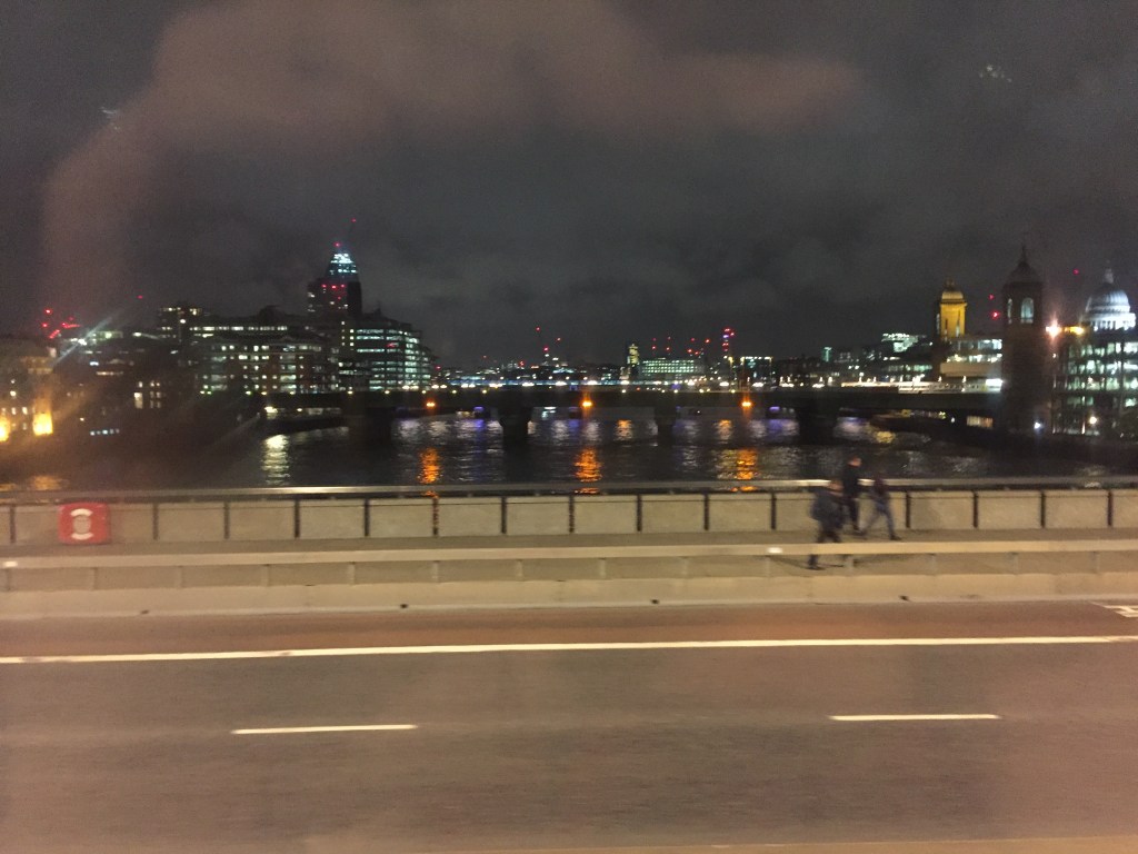 Night view down the Thames from London Bridge, with buildings and bridges lit up in the distance.