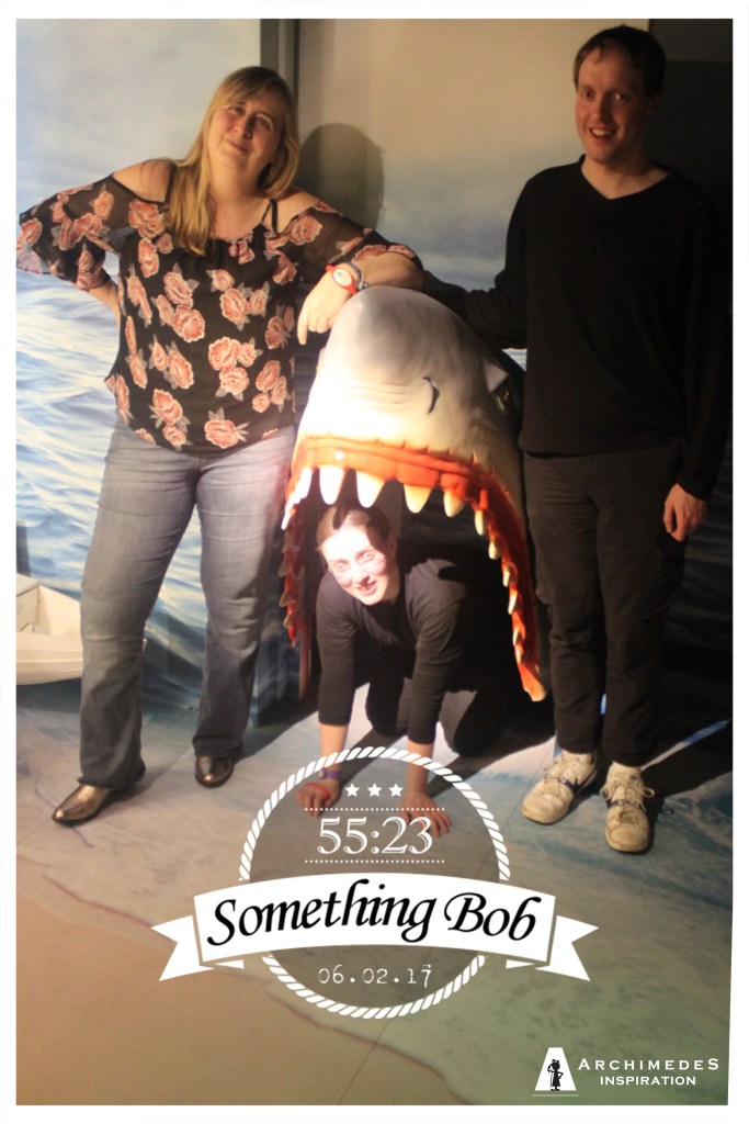 Myself a lady standing beside a model of a shark head by the wall. The other guy in our group is crouched down inside the shark's gaping mouth. A graphic at the bottom shows our team name - Something bob - with a time of 55 minutes and 23 seconds, and the date of February 6th 2017.