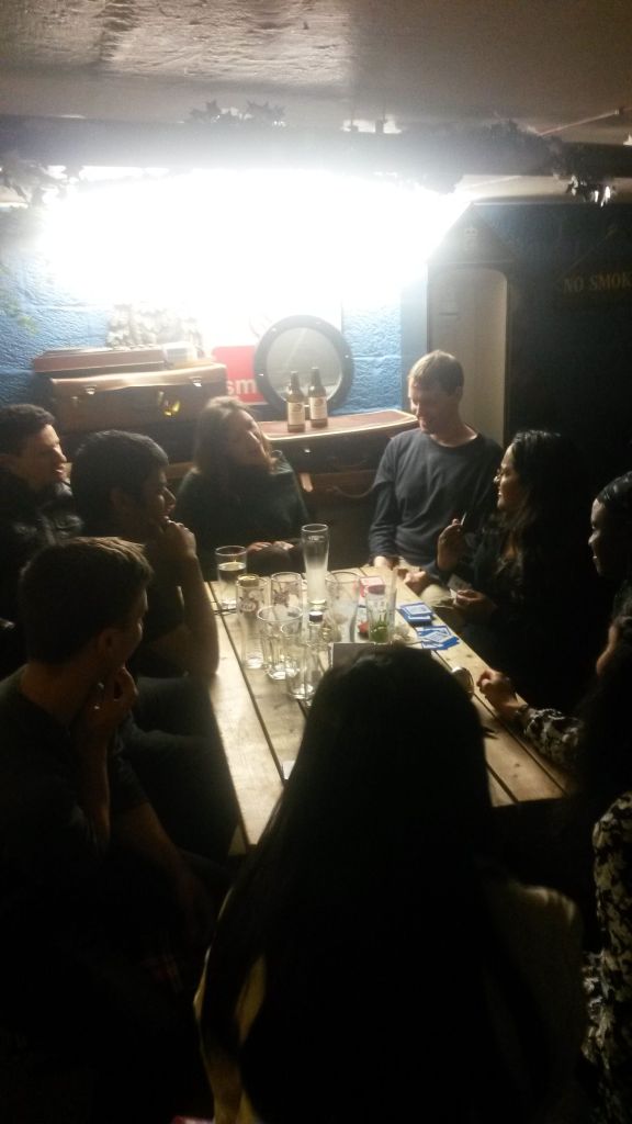 Me among a group of people sat around a pu table, with playing cards and lots of empty glasses on the table