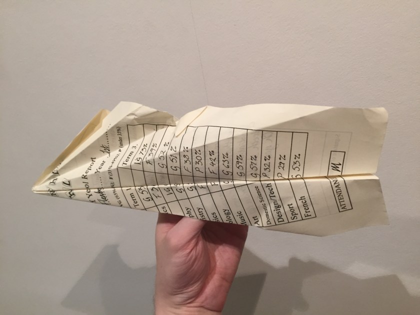A school report folded in the shape of a paper aeroplane.