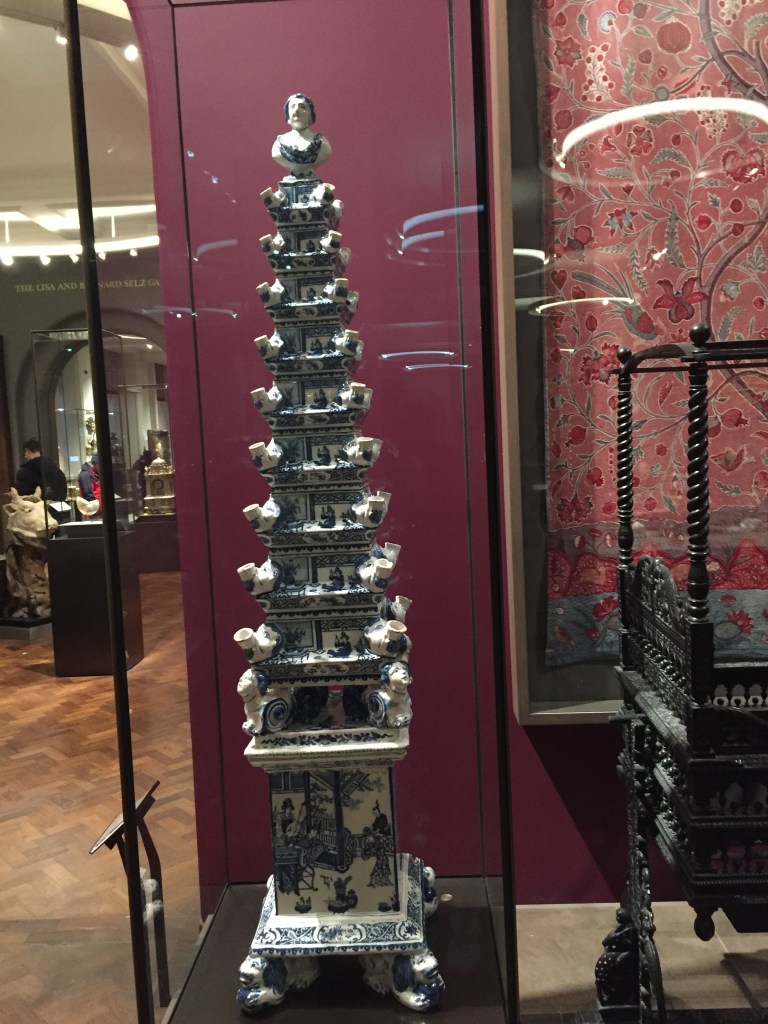 A narrow pyramid structure on a short column, designed to sit on a table. The pyramid narrows towards the top, and is made of many layers that have a holder on each side for standing a flower in.