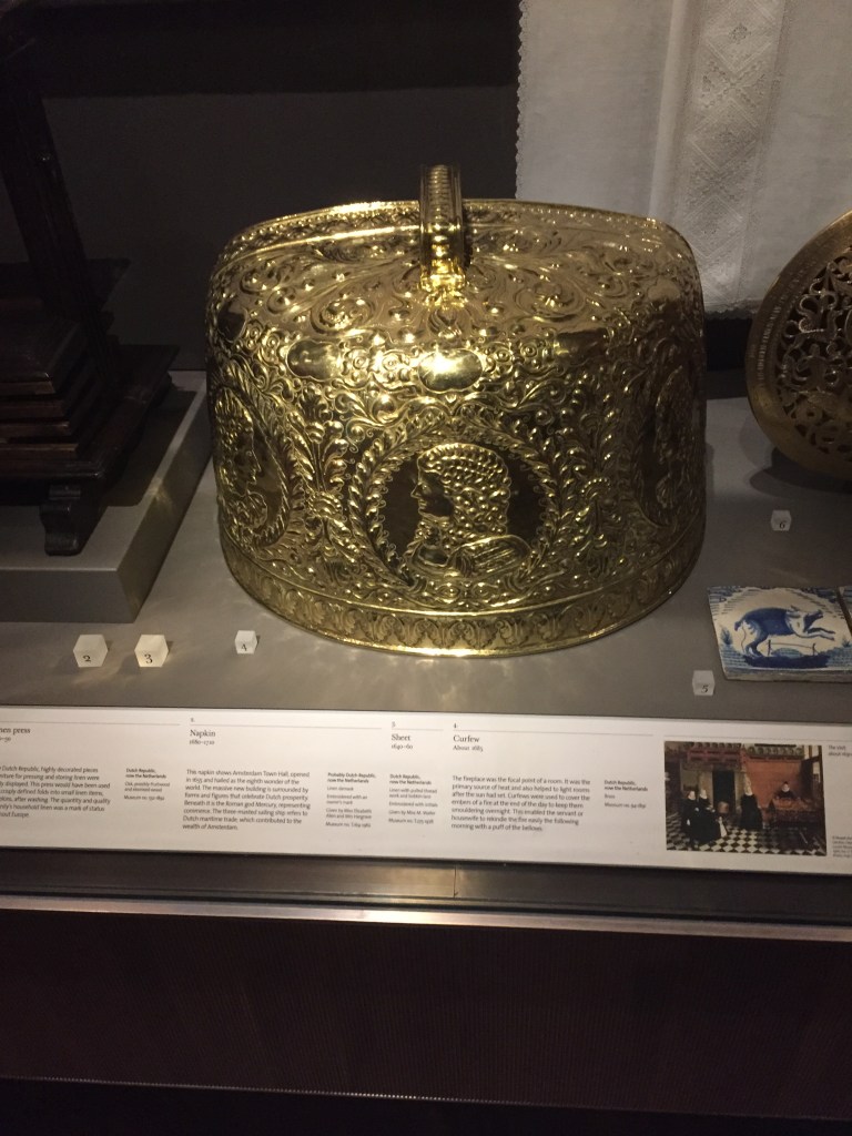 A large, gold and very ornately decorated gold dome with a handle on top, called a curfew, for placing over the smouldering embers of a fireplace, to keep them smouldering to enable easy relighting the next morning.