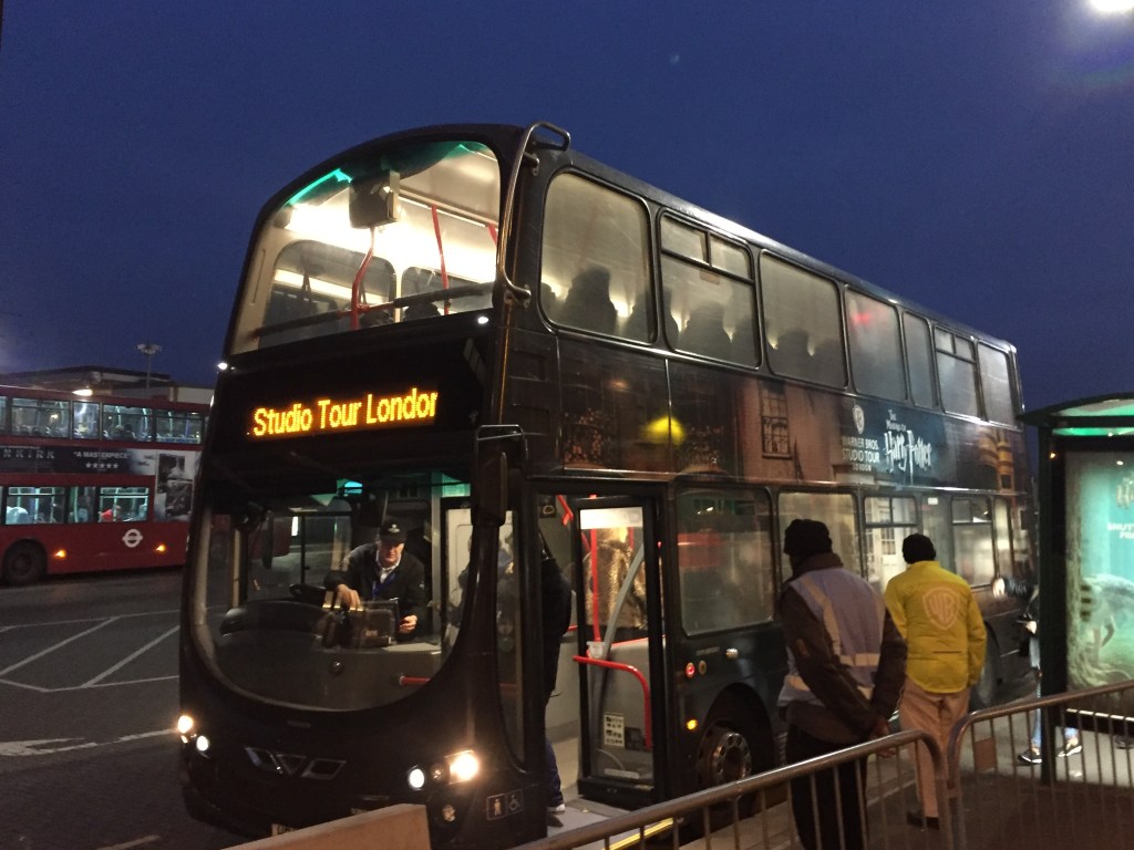 Double-decker coach with Studio Tour London on the front destination panel, and artwork on the side of the bus sowing that it's for the Harry Potter studio tour.