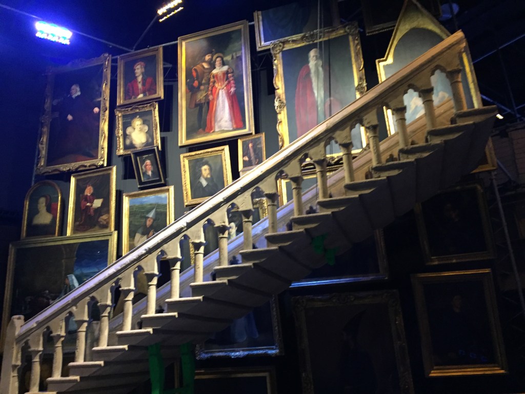 Staircase with portraits of various sizes on the wall behind it.
