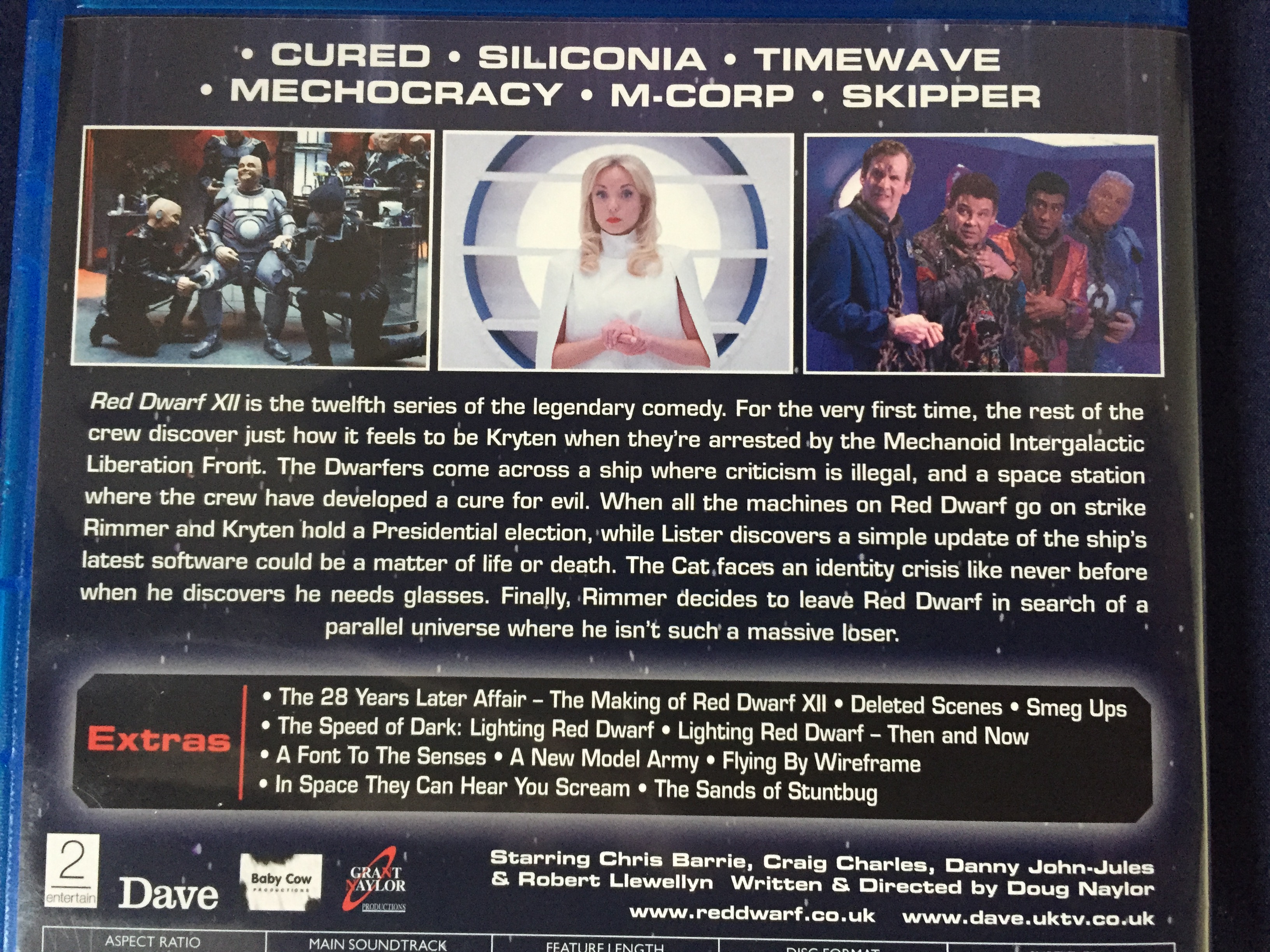 Rear of the Blu-ray case for Red Dwarf series 12, including episode titles, screenshots and a general description of the show, plus a list of extras including a behind-the-scenes documentary and featurettes, deleted scenes and smeg ups.