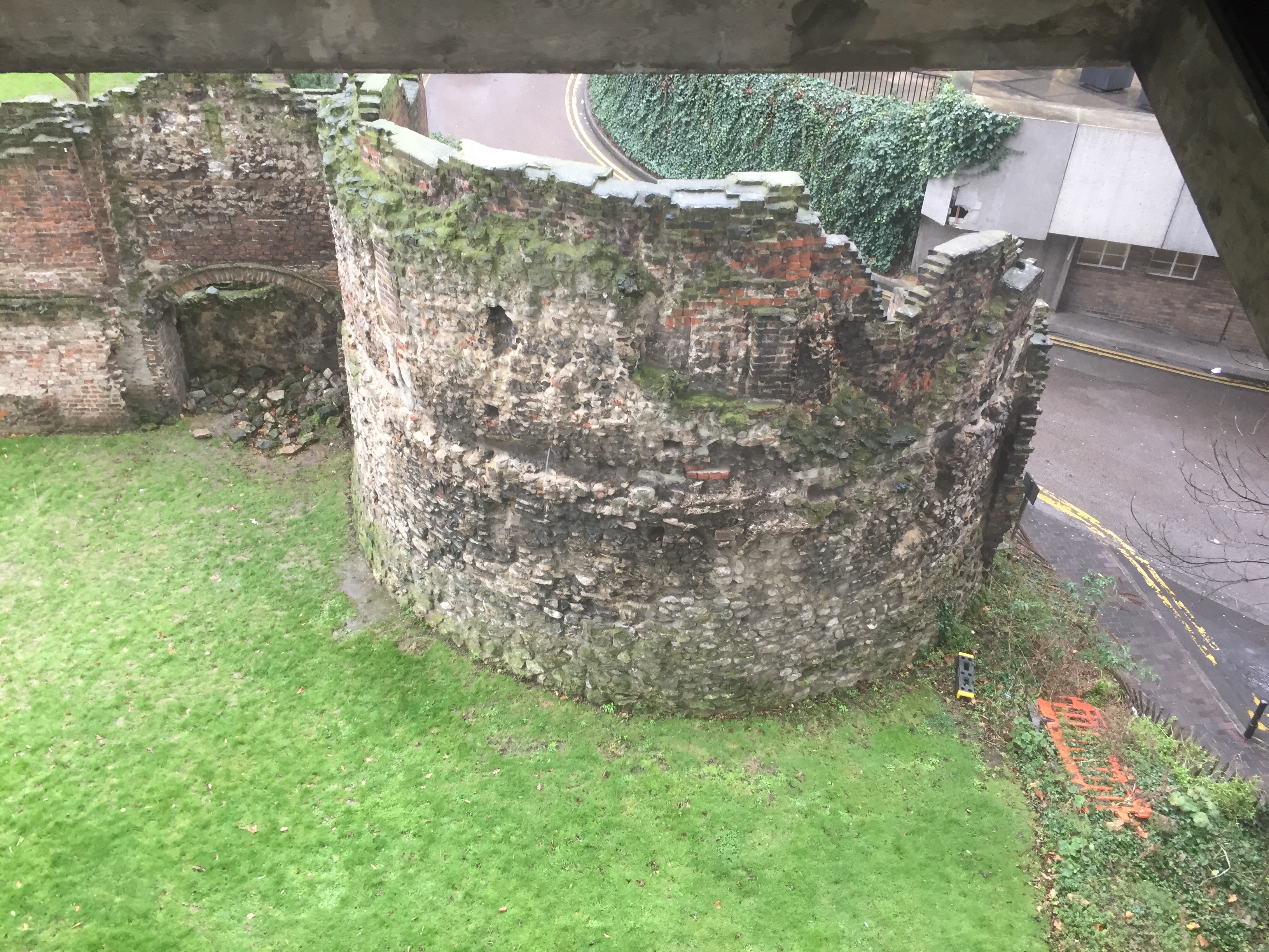 A large round section of the Roman stone wall that used to surround London. now partly in ruins with pieces missing at the top
