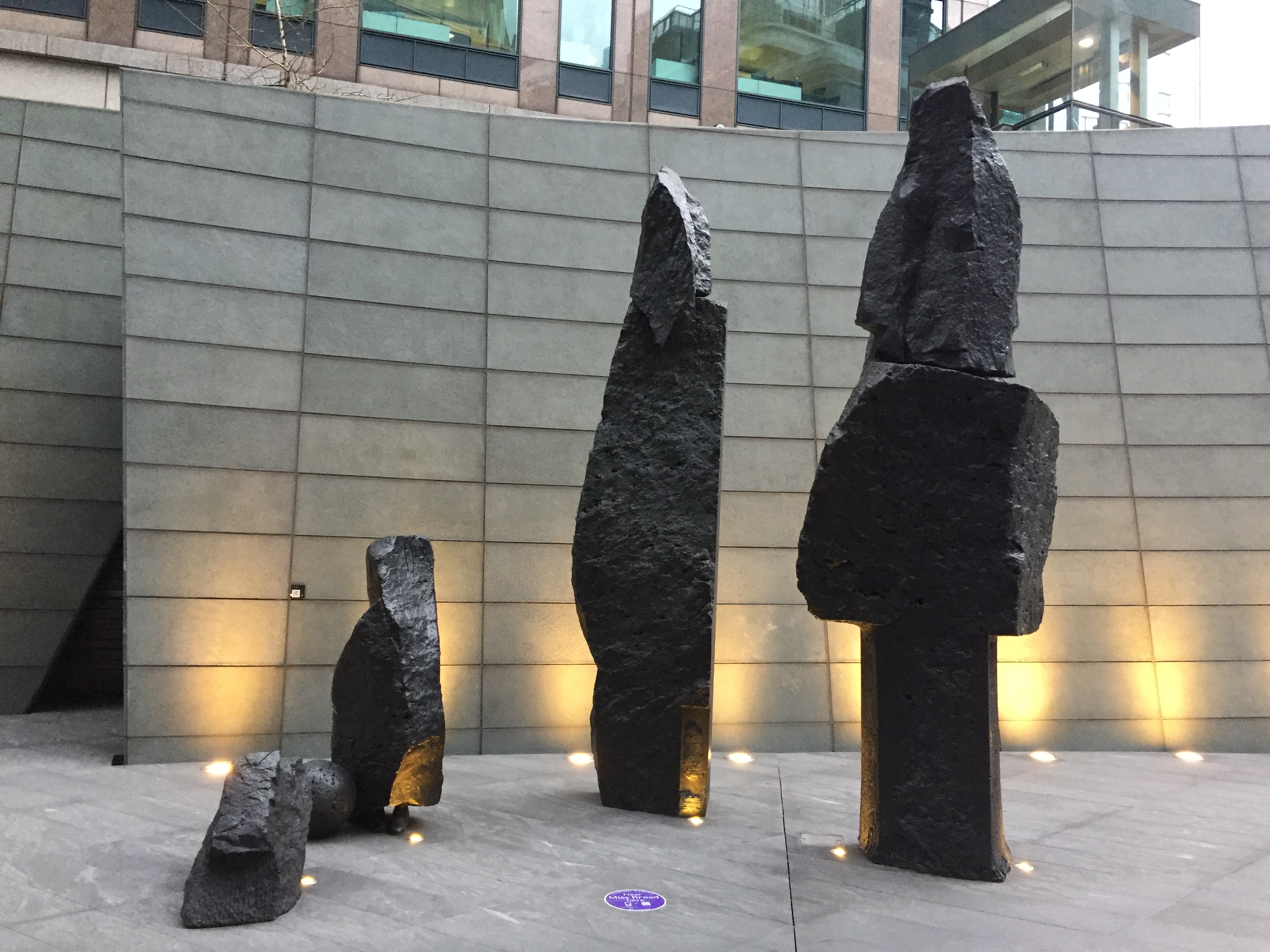 4 dark stone statues, 2 tall and 2 short. They have a very rough, indistinct form that doesn't look like anything in particular. But they are placed to look like a family, with the 2 taller parent statues overseeing the 2 smaller child ones.