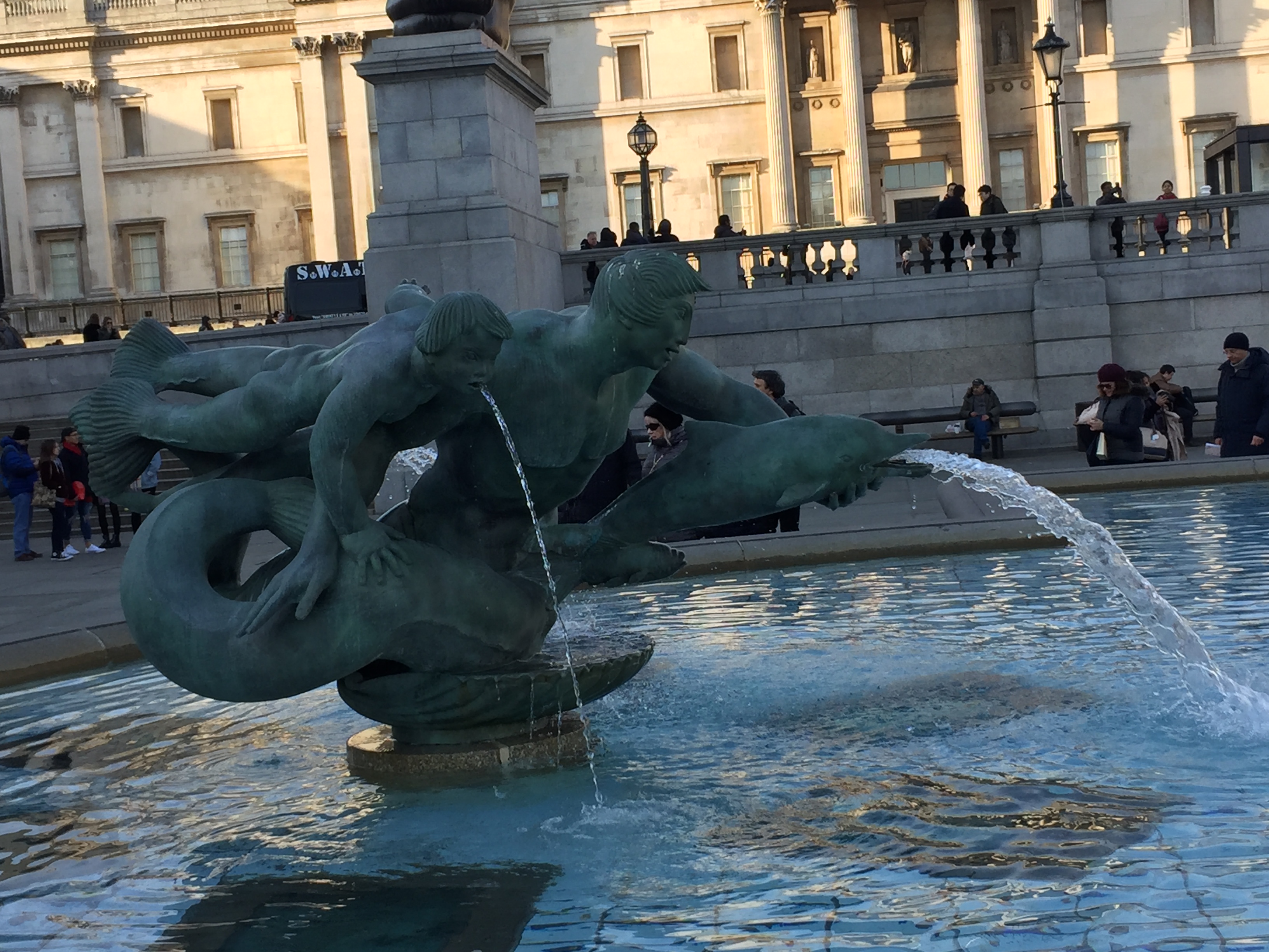 Fountain statue of a man holding a fish under his left arm, and a boy under his right arm, each of which is spewing out a stream of water.