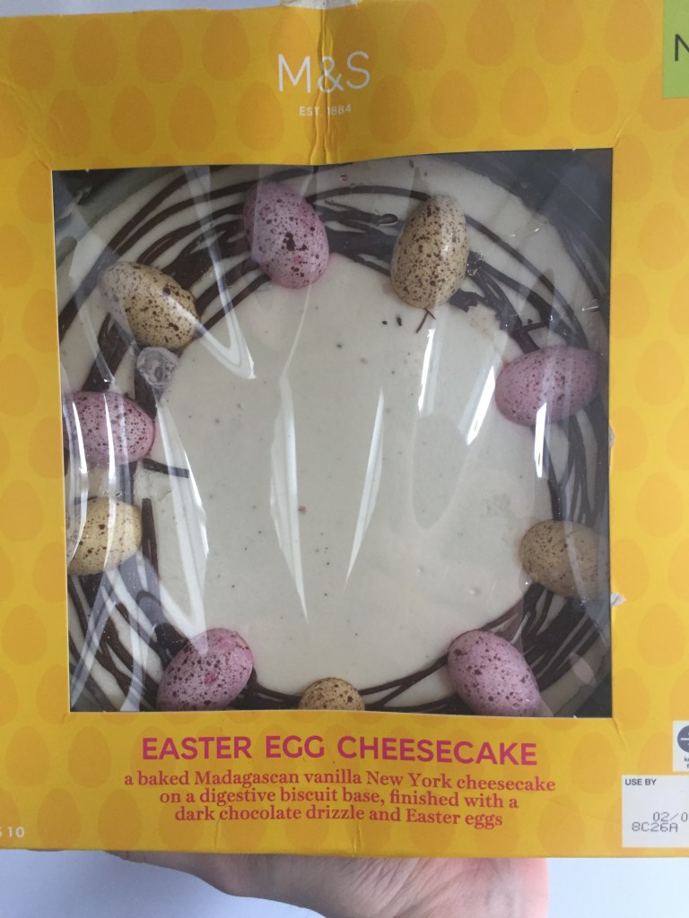 Large cheesecake with chocolate swirls and coloured chocolate eggs around the edge.