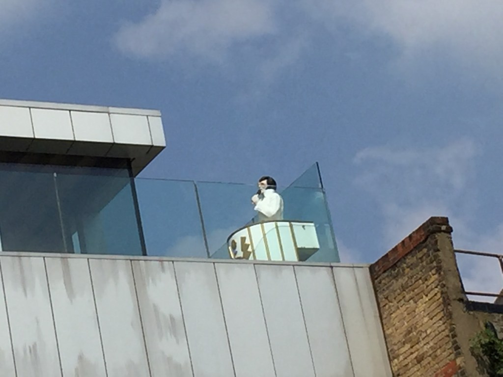 Model of Elvis Presley dressed in white and singing, on top of a building by the Grand Union Canal.