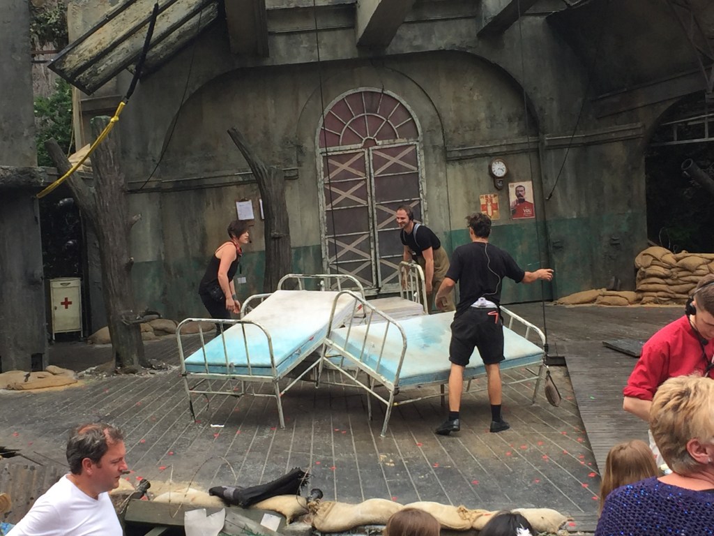 Stage crew moving 3 beds on stage during the interval. The beds had been stacked against each other at angles to represent a rocky mound.