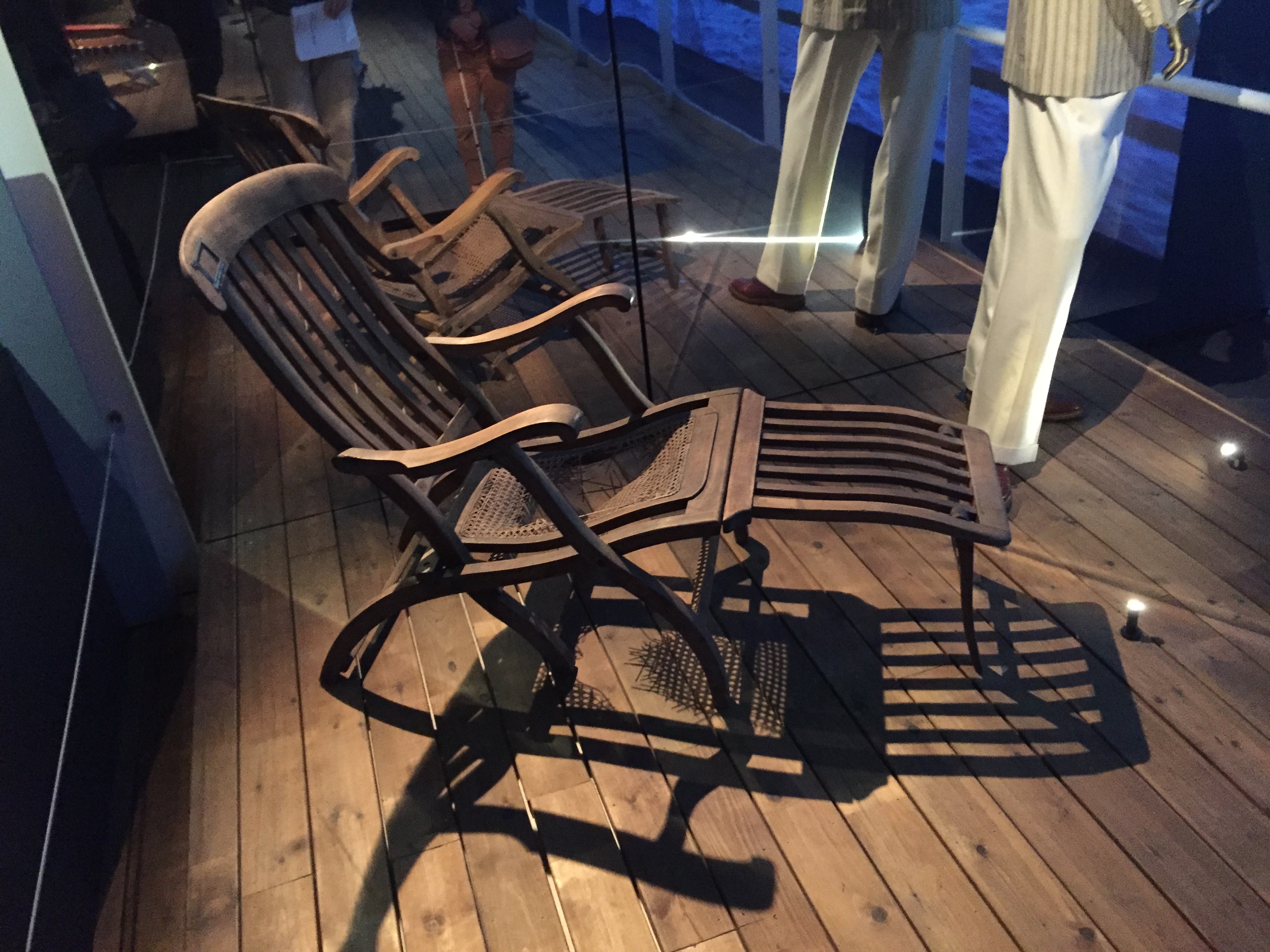 Reclining wooden deckchair, with slats in the wood on the back and leg rest.