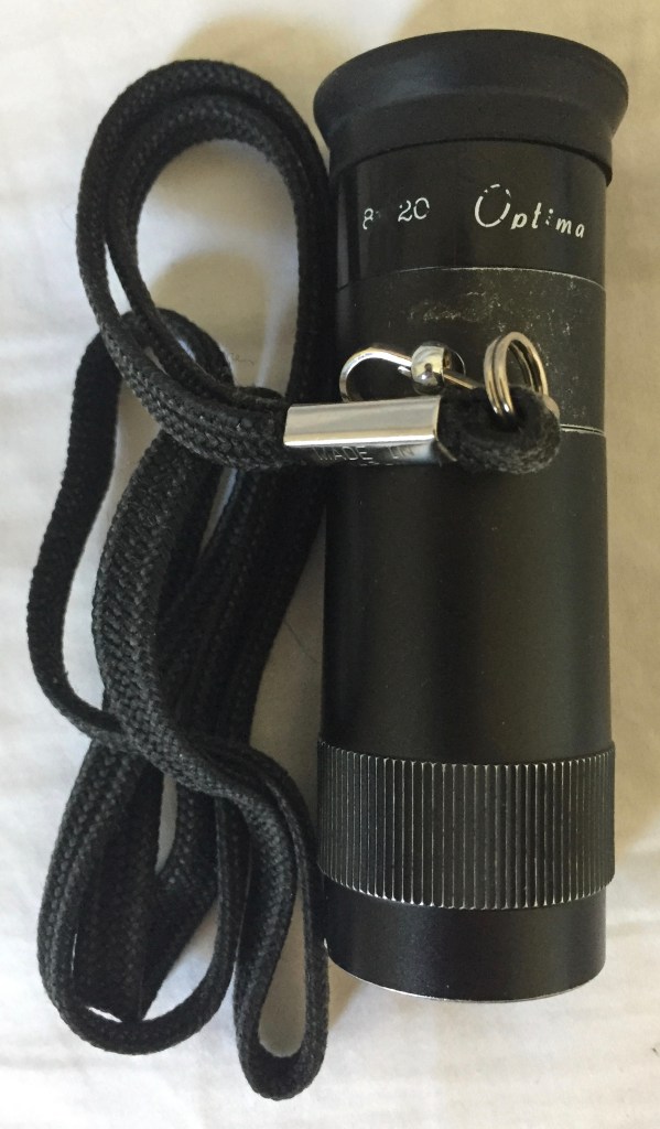 My monocular, a small black telescope with a rubber ring attached to the eyepiece end for comfort, and a cord attached on the side so you can hang it around your neck.