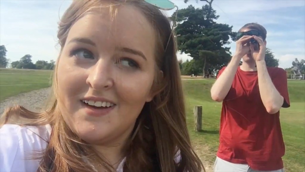 Emily Davison talking to the camera in a sunny green park, while I use my monocular to look around me in the background.