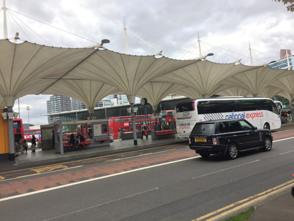 Stratford bus station, with a white National Express coach parked under the curved, undulating, cream coloured canopy