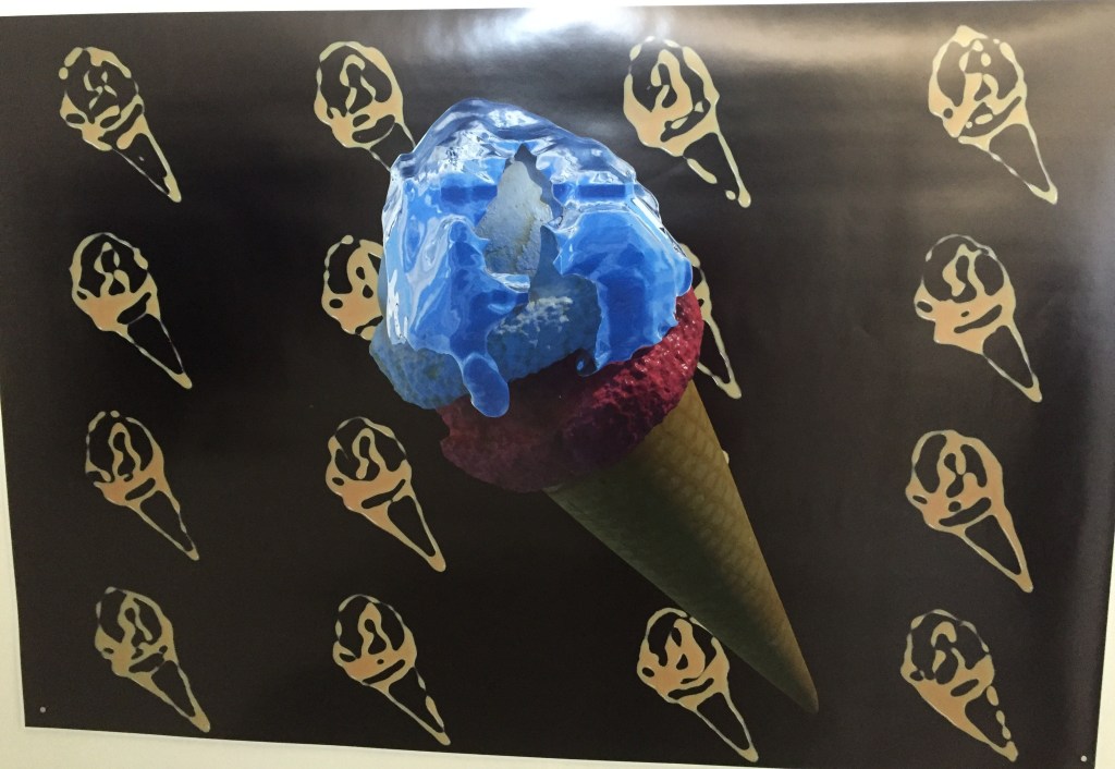 An artistic print of a large ice cream cone with blue and white ice cream on the top, against a background of repeating ice cream silhouettes in a golden colour against a black background.
