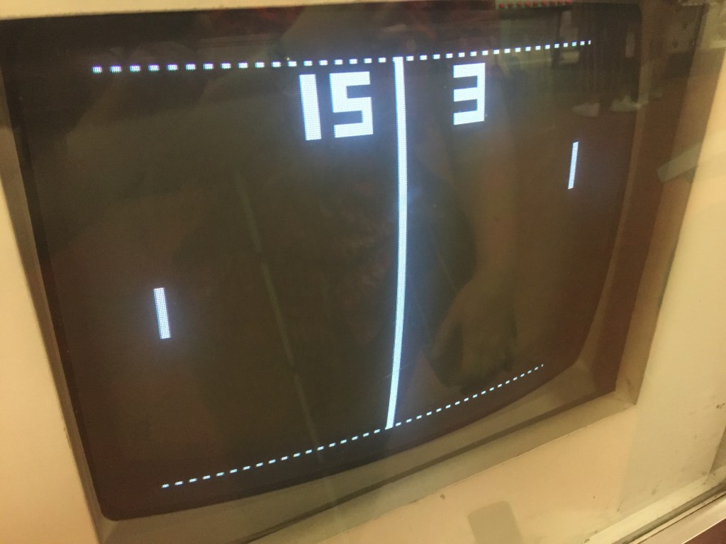 Monitor showing a game of Pong, where each player moves a small white line up and down their side of the screen, in order to knock a small dot across to the other player, much like tennis. This game has finished, and the score is 15-3.