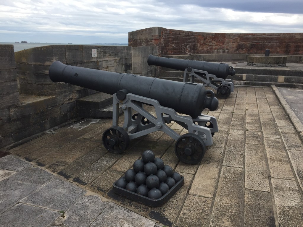 2 large cannons and a pyramid stack of cannonballs on top of Southsea Castle.