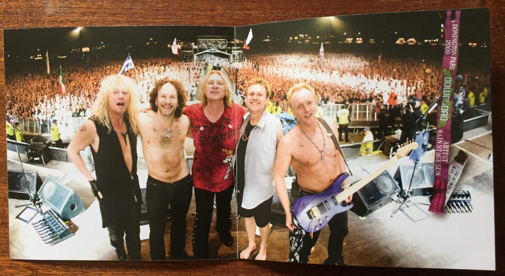 Centre spread of the booklet from the Mirrorball album, a photo of the 5 band members on stage with the huge crowd lit up behind them.