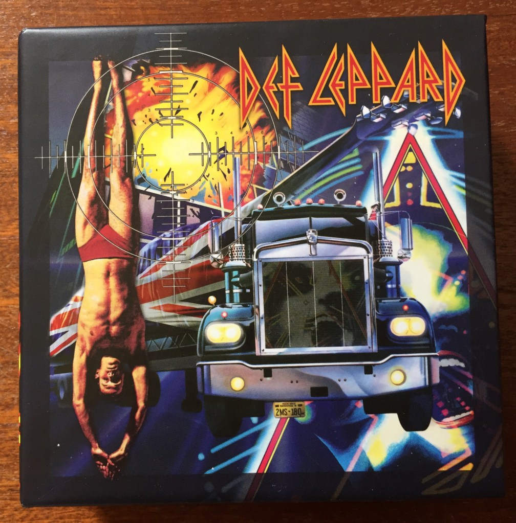 Cover for the Def Leppard CD Collection Volume 1 boxset. The cover mixes imagery from the album covers in the set, including a speeding truck, a man diving, an explosion, and the triangular logo from Hysteria.