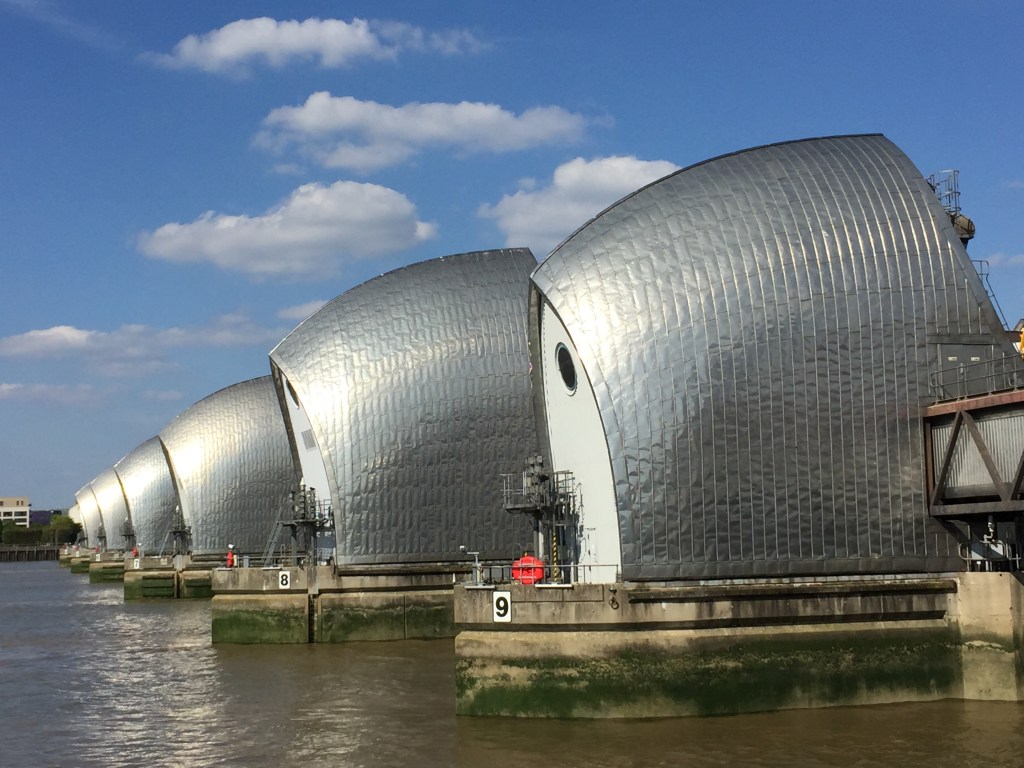 The Thames Barrier, with its 9 curving silver structures at regular intervals across the river.