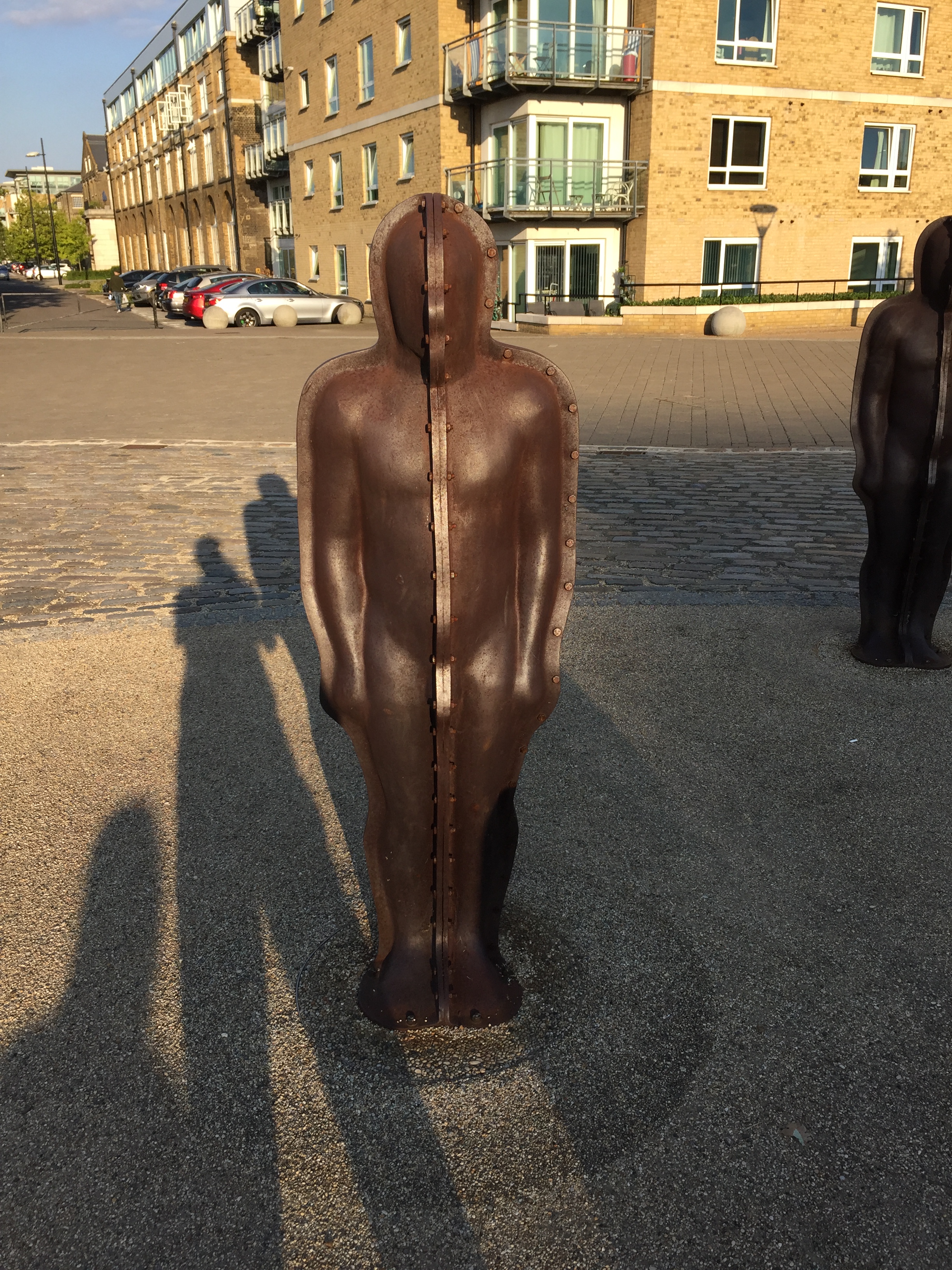 An iron statue of a generic male figure, among a group of similar statues.