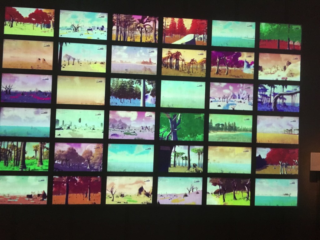 A large wall filled with a grid of screens, showing the many different terrains and features of just some of the planets in the game No Man's Sky.