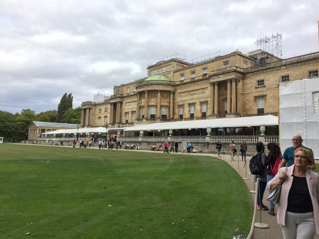 Rear view of Buckingham Palace, which overlooks a large lawn.