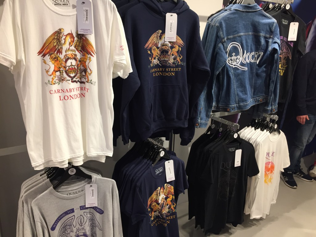 Various t-shirts and a denim jacket for sale in the Queen shop.