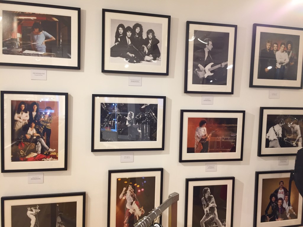 Photo gallery on the wall in the Queen shop, with pictures of Queen and Freddie Mercury in promotional shots, working in the studio and performing live on stage.