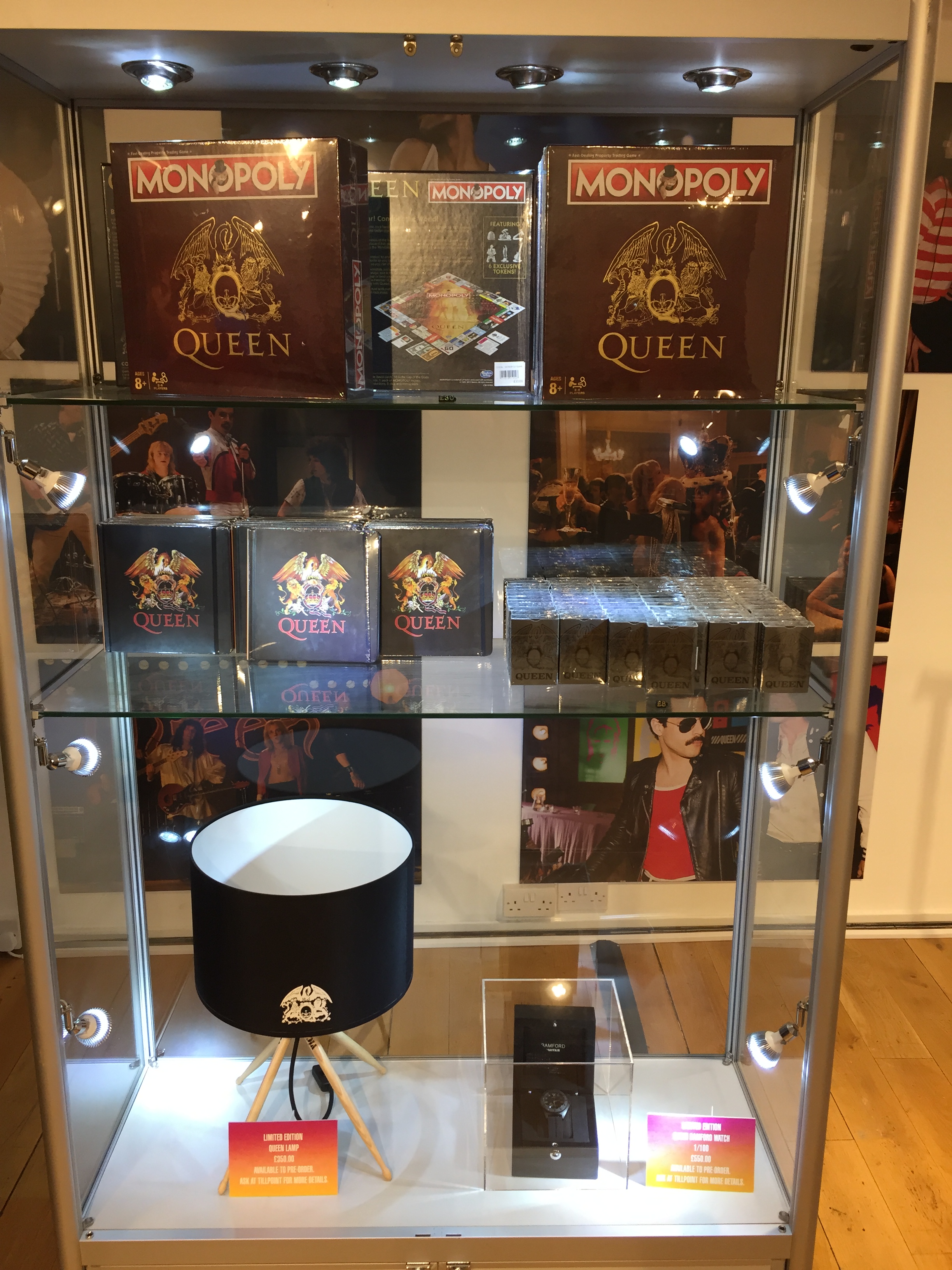 Glass shelving in the Queen shop featuring Queen Monopoly, playing cards, notebooks, a limited edition lamp and a limited edition watch.