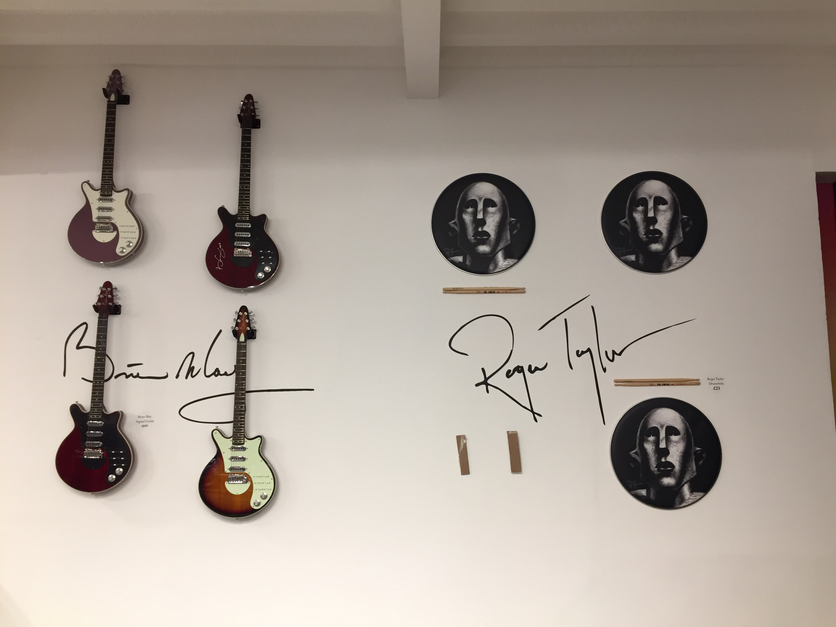 Wall display in the Queen shop with 4 electric guitars signed by Brian May, and drumsticks from roger Taylor.