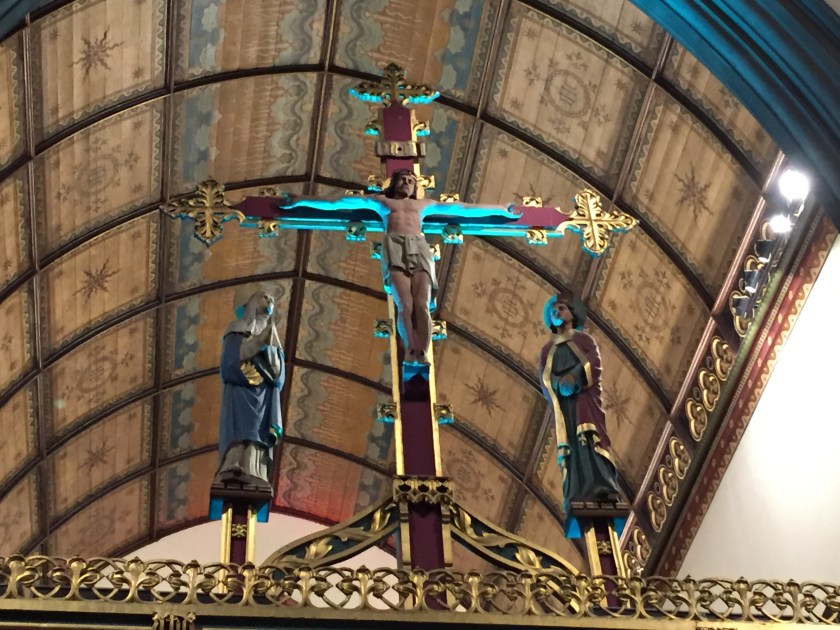 A statue of Jesus on a large ornate cross with religious statues stood on each side.