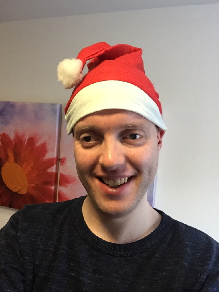 Glen smiling and wearing a red and white Santa hat.