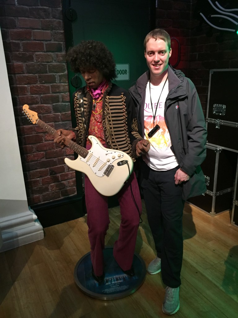 Glen posing with a waxwork of Jimi Hendrix at Madame Tussauds. Hendrix is looking down at the white and cream coloured guitar in his hands as if about to play.