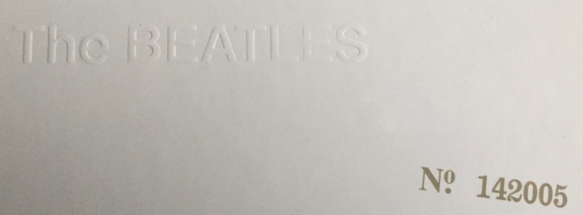 Close-up of the bottom right corner of the cover for the White Album box set by The Beatles. On the white background is white, embossed, tactile text that says The Beatles. To the right and slightly below this is text stamped on in light grey that says Number 142005.