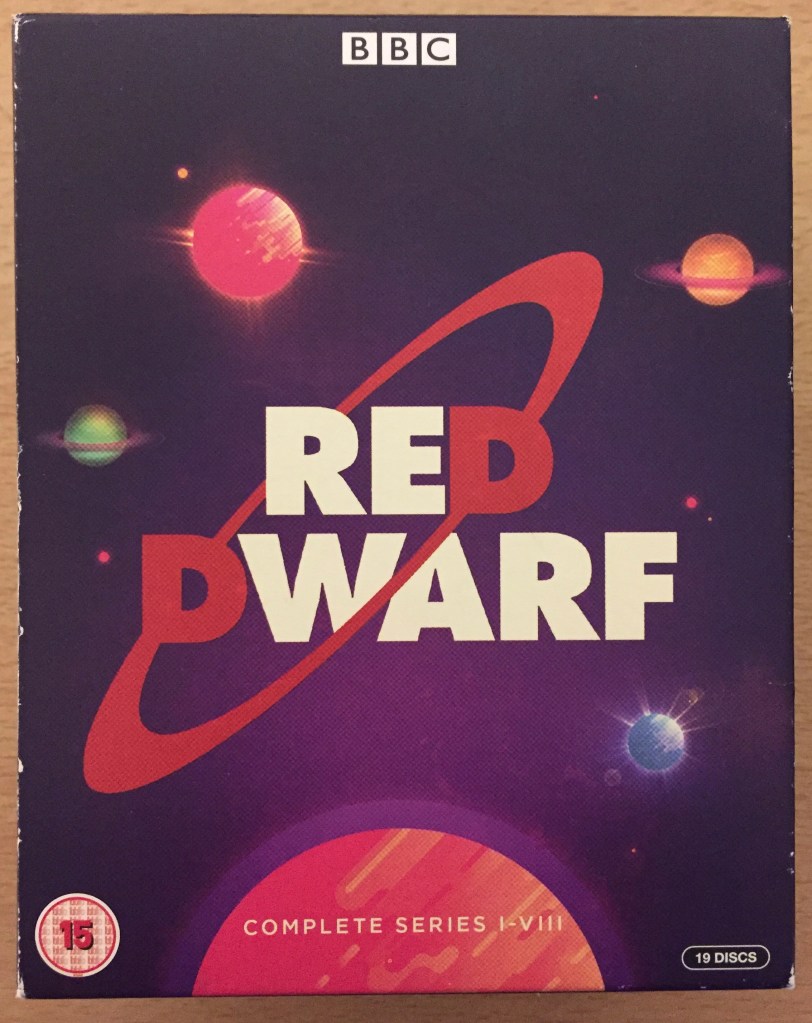 Cover of the Red Dwarf Series 1 to 8 Blu-ray box set. The logo consists of large capital letters saying Red Dwarf, one line above the other. All letters are white, except for the letter D on each line, which is red. Those 2 letters are connected by a red ring at a diagonal angle, passing behind the word Red and in front of the word Dwarf. This is all against a dark blue-ish purple background showing various coloured planets in space.