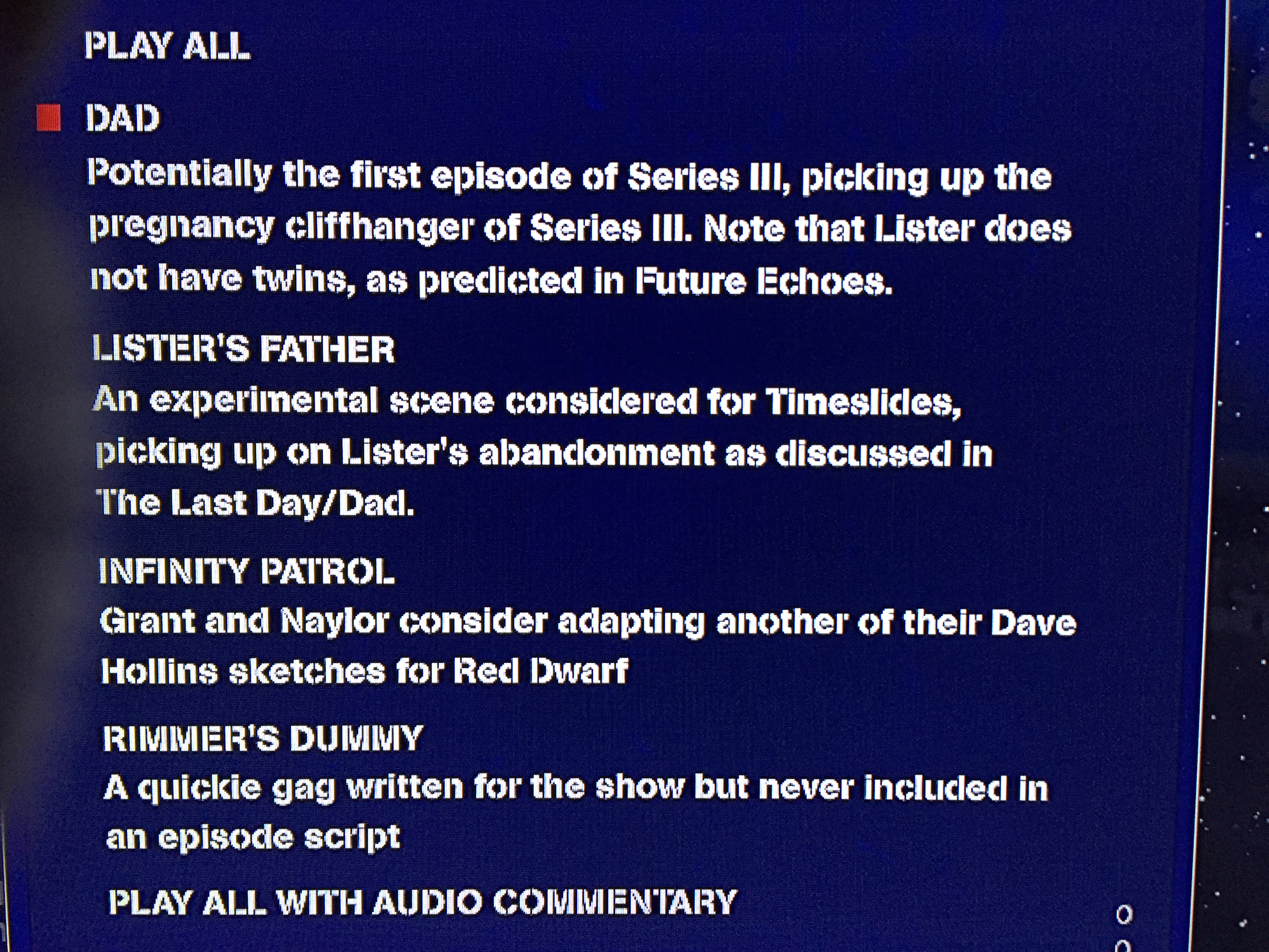 Close-up of the script extracts menu on the Red Dwarf Blu-ray box set Bodysnatcher disc, with white text on a dark blue background. Titles include Dad, Lister's Father, Infinity Patrol and Rimmer's Dummy, plus options to play them all together, with or without audio commentary.